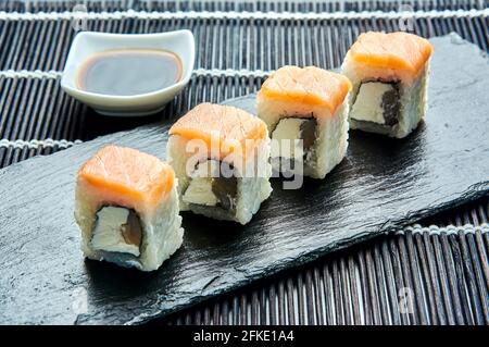 Rotolo classico di Philadelphia con gamberi su una pietra scura su una tavola. Sushi giapponese. Foto Stock