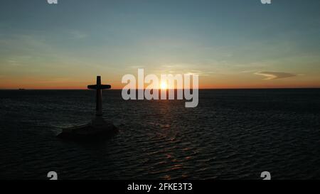 Croce cattolica nel cimitero affondata nel mare al tramonto, antenna fuco. colorato cielo durante il tramonto. Grandi crucafix segnando il sottomarino sunken cimitero, CAMIGUIN ISLAND Filippine. Foto Stock