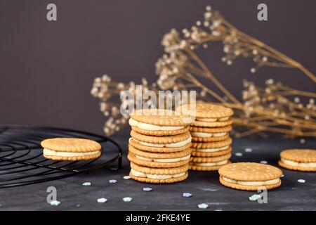 Biscotti doppi sandwich riempiti con panna bianca su sfondo scuro Foto Stock