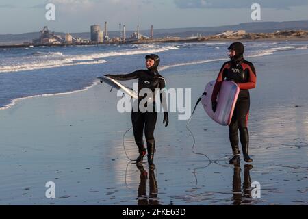 Olivia Harris (a sinistra) e il suo amico Rachel che naviga a Seaton Carew, Inghilterra nord-orientale con Redcar Steelworks in lontananza. Foto Stock