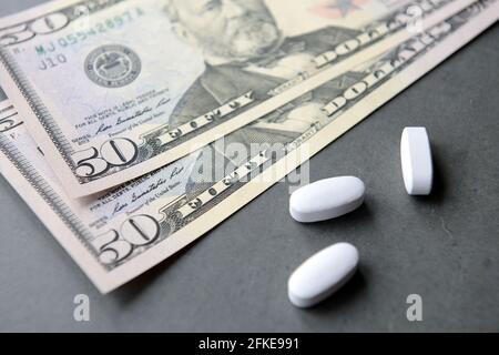 Pillole o droghe e dollari denaro contante su uno sfondo scuro. Foto Stock