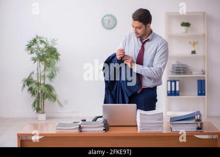 Giovane impiegato di sesso maschile e troppo lavoro in ufficio Foto Stock