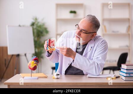 Vecchio insegnante di dentista seduto in classe Foto Stock