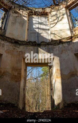 Vista attraverso i fori per porte e finestre in un rovina abbandonata nei boschi Foto Stock