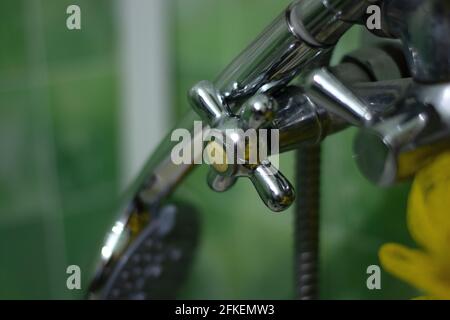 il soffione della doccia poggia sui rubinetti contro un verde sfondo parete Foto Stock