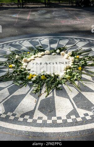 I fiori circondano il mosaico vivente del memoriale 'Imagine' che è un tributo a John Lennon dei Beatles, Central Park, New York City, USA Foto Stock