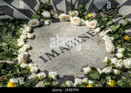 I fiori circondano il mosaico vivente del memoriale 'Imagine' che è un tributo a John Lennon dei Beatles, Central Park, New York City, USA Foto Stock