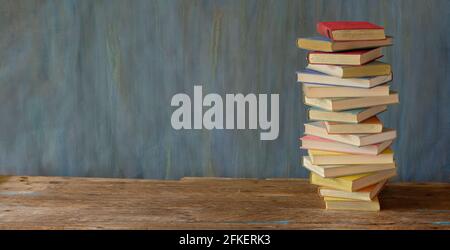 Grande pila di libri su sfondo scuro. Lettura,letteratura,educazione,biblioteca,home Office, back to School Concept,panoramica, grande spazio libero per la copia Foto Stock
