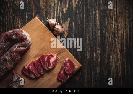 Affettare a scatti e un paio di spicchi d'aglio su un tagliere di legno. Drogheria di fondo rurale. Foto Stock