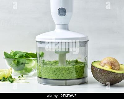 avocado, sedano e spinaci in contenitore trasparente in plastica per preparare un sano frullato da colazione sul tavolo da cucina Foto Stock