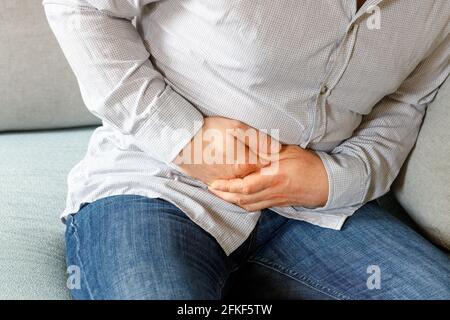 L'uomo nella camicia afferrando il suo stomaco dolorante Foto Stock