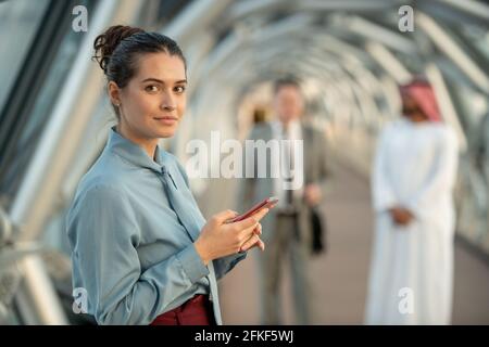 Giovane donna d'affari che guarda giovani mentre usa il telefono cellulare Foto Stock