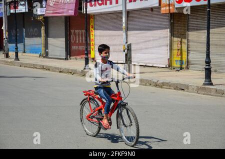 Srinagar, India. 01 Maggio 2021. Un ragazzo corre il suo ciclo attraverso un mercato chiuso durante un blocco imposto dalle autorità a seguito dell'aumento dei casi di coronavirus in Srinagar.Jammu e Kashmir continuano a rimanere sotto stretto blocco il Sabato a seguito dell'aumento dei casi COVID-19. Le severe restrizioni continueranno fino al lunedì mattina. Nel frattempo, l'India ha raggiunto un nuovo record giornaliero con 4, 02,000 nuovi casi di COVID-19 e 3,521 morti nelle ultime 24 ore. (Foto di Saqib Majeed/SOPA Images/Sipa USA) Credit: Sipa USA/Alamy Live News Foto Stock