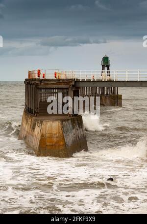 Una giornata molto ventosa sul molo Whitby, nello Yorkshire del Nord, Inghilterra. Whitby è una città storica con le sue strade stravaganti, i negozi e le rovine dell'abbazia. Foto Stock