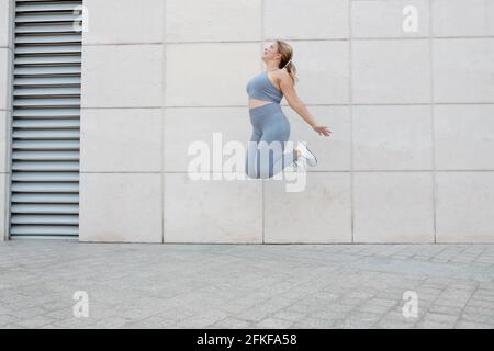 Felice eccitata più la giovane donna di taglia che salta in alto dentro l'aria Foto Stock