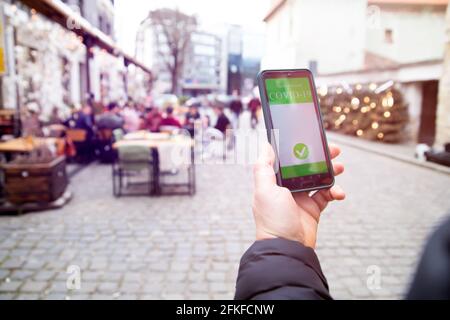 Vaccinato con certificato di immunizzazione su smartphone al ristorante o in terrazza. Foto Stock