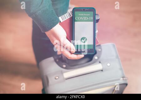 Persona vaccinata che usa l'app per passaporto sanitario digitale sul telefono cellulare per viaggiare durante la pandemia di covid-19 Foto Stock