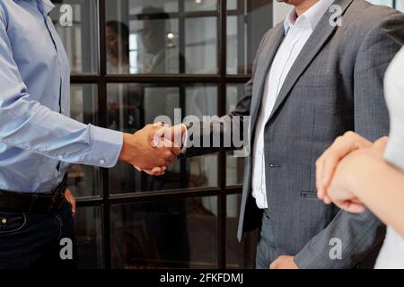 Immagine ravvicinata di persone che scuotono le mani per terminare la riunione o la negoziazione Foto Stock