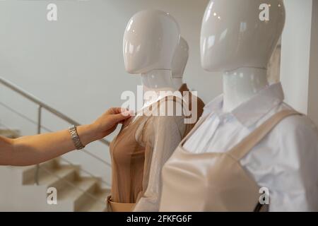 La mano di una donna tocca i vestiti su un manichino prima del montaggio. Copspace Foto Stock