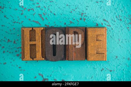 Hope scritto in legno tipo Imposta lettere di blocco su a. Sfondo turchese Foto Stock