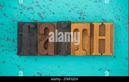 Faith scritto in legno tipo Imposta lettere di blocco su a. Sfondo turchese Foto Stock