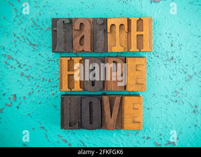 Fede speranza e amore scritto in legno tipo blocco set Lettere su sfondo turchese Foto Stock