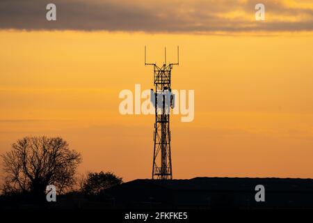 5G controverso radiotelefono radiotelefono radiotelefono silhouette palo del trasmettitore al tramonto dell'ora d'oro. Cielo estivo con nuvole e alberi. Foto Stock