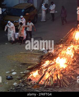 Nuova Delhi, India. 01 Maggio 2021. I lavoratori e i membri della famiglia portano un corpo per la cremazione vicino a più pire funerarie delle vittime di COVID-19 bruciare su un terreno che è stato convertito in un crematorio per la cremazione di massa a Nuova Delhi, India il Sabato, 1 maggio 2021. Foto di Abhishek/UPI Credit: UPI/Alamy Live News Foto Stock