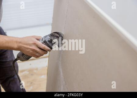 Uomo che taglia cartongesso su fori tagliati usando l'angolo utensili  elettrici manuali per elettricista con interruttore per luci da parete Foto  stock - Alamy