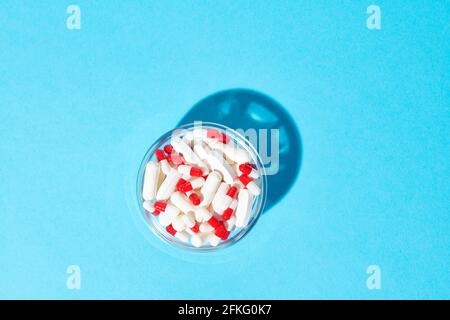 Capsule rosse e bianche e pillole bianche in ciotola Foto Stock