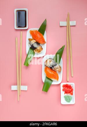 Set di sushi con tristini e salsa di soia su sfondo rosa minimalista. Foto Stock