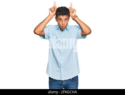 Giovane bell'uomo afroamericano che indossa abiti casual che fanno divertente gesto con il dito sulla testa come corna toro Foto Stock