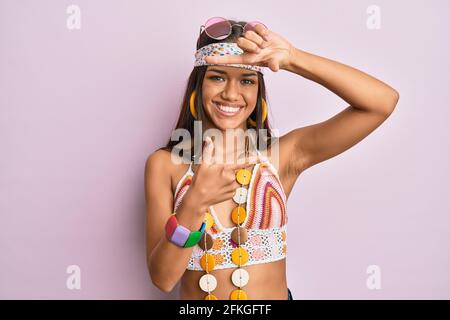 Bella donna ispanica che indossa stile bohémien e hippie sorridente rendendo cornice con mani e dita con viso felice. Creatività e fotografia con Foto Stock