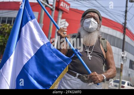 San Salvador, El Salvador. 01 Maggio 2021. Un protetore che indossa una maschera facciale tiene una bandiera Salvadorana durante la dimostrazione.i lavoratori scesi per le strade durante la giornata internazionale dei lavoratori in mezzo alla pandemia COVID-19. (Foto di Camilo Freedman/SOPA Images/Sipa USA) Credit: Sipa USA/Alamy Live News Foto Stock