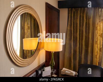 Frammento di interni di moderna camera d'albergo arabica con lampada, finestra, tavolo e telefono Foto Stock