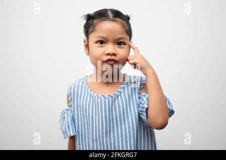 Ritratto di bambino asiatico di 5 anni e per raccogliere i capelli e mettere il dito indice alla testa e fare pensare posa su sfondo bianco isolato, lei Foto Stock