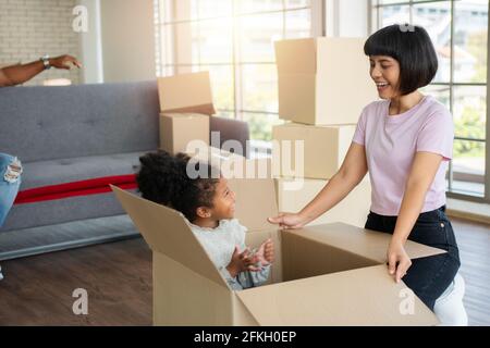 Le famiglie di razza mista sono sedute sul divano per riposare dopo essersi spostate in una nuova casa il primo giorno dopo l'acquisto del bene immobile. Concetto di iniziare un nuovo Foto Stock