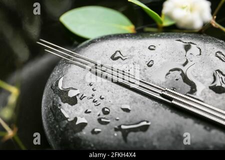 Aghi di agopuntura su pietra termale, closeup Foto Stock