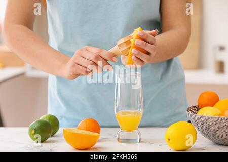 Donna che fa succo d'arancia su tavolo luminoso in cucina Foto Stock