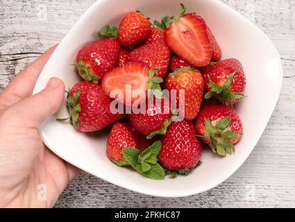 Concetto di alimentazione sana. Ciotola da donna con fragole fresche. Direttamente sopra. Foto Stock