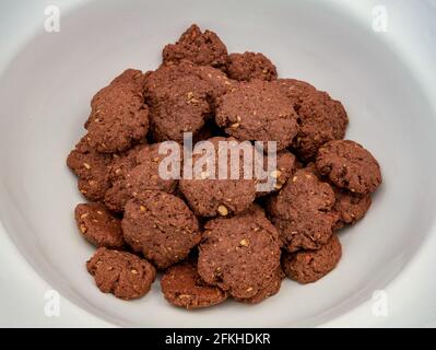 Biscotti fatti in casa al cioccolato con noci, su un mucchio in una grande ciotola bianca Foto Stock