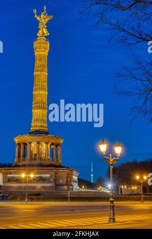 La famosa colonna della Vittoria con una luce di strada e rami di alberi a Berlino, in Germania, di notte Foto Stock
