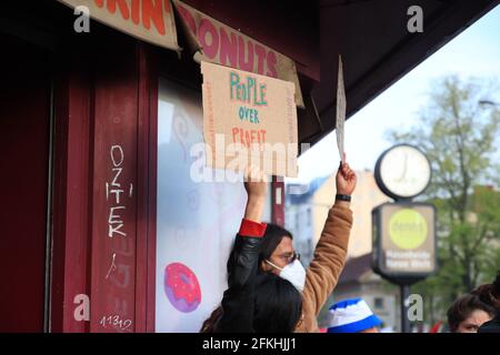 Berlino, Germania - 01 maggio 2021: Un protetore che tiene un cartello con la scritta "persone in più del profitto" alle manifestazioni del 1° maggio per le strade di Berlino Foto Stock