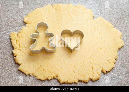 Sfoglia l'impasto e taglia i biscotti a forma di cuore e uomo per la cottura di biscotti fatti in casa per le vacanze di San Valentino. Concetto di cottura fatto in casa. Solitudine Foto Stock