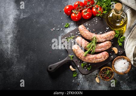 Bratwurst o salsicce sul tagliere con spezie al tavolo nero. Foto Stock