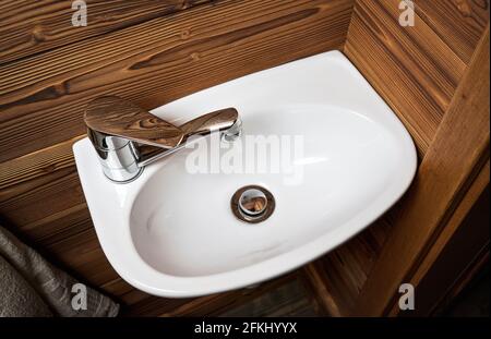 Piccolo lavabo bianco, pareti in legno intorno, dettaglio guardaroba Foto Stock