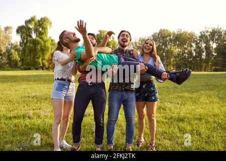 Giovani amici allegri che si divertono in campagna il giorno d'estate. Gruppo di persone che ridono ed essendo sciocco nella natura Foto Stock