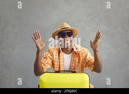 Studio ritratto di un felice allegro turista nero con il suo valigia da viaggio gialla Foto Stock
