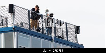 Cameraman e broadcaster in diretta in streaming un gioco della scuola superiore dalla parte superiore della casella stampa sui bleachers. Foto Stock