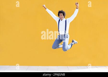 Uomo nero con capelli afro che salta su una città gialla sfondo Foto Stock